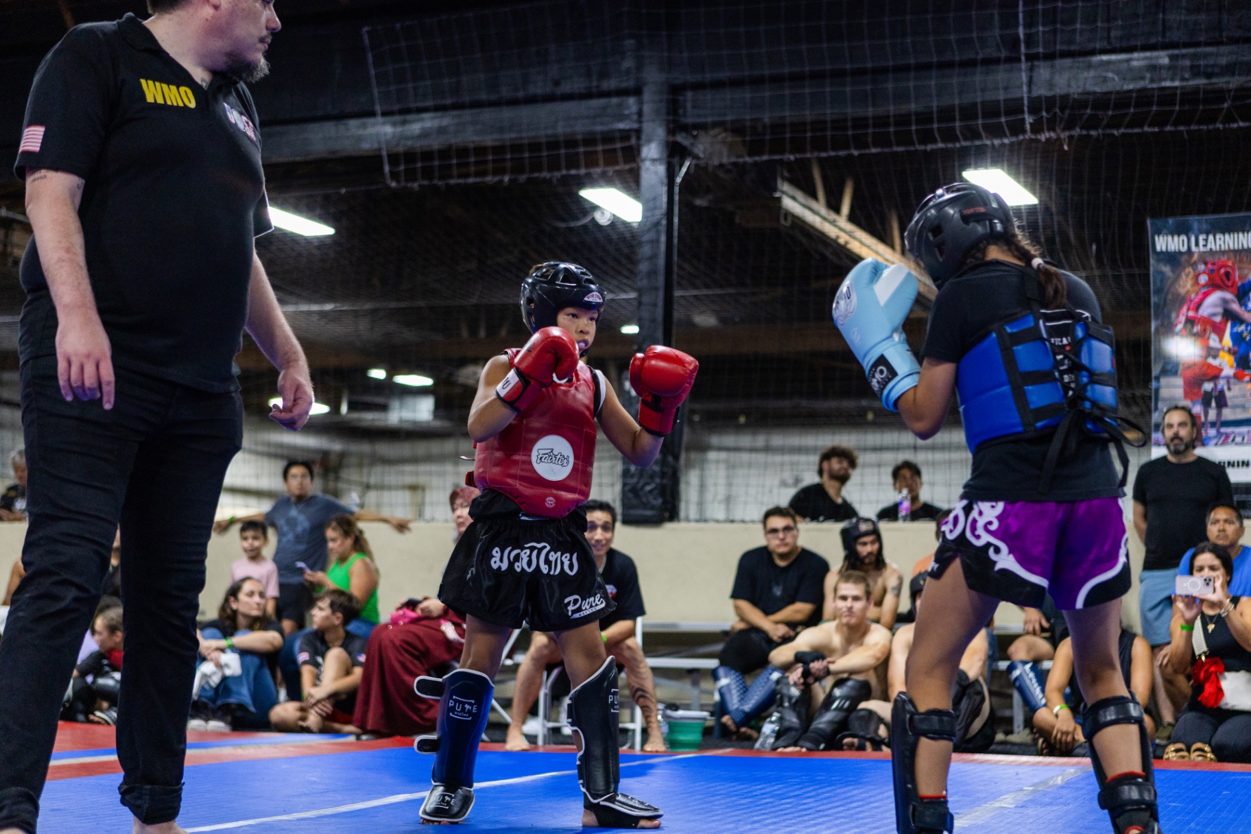 Youth Muaythai athletes sparring under a WMO referee at a Learning League event